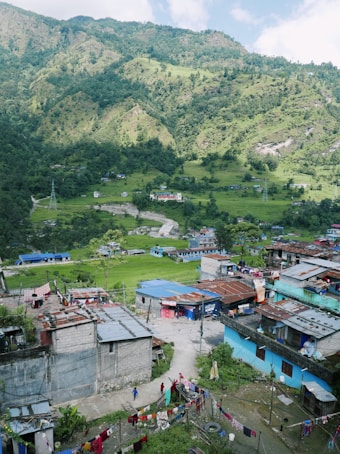 a group of buildings and trees with a hill in the background