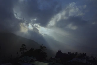 Radiant light beams breaking through clouds over a tranquil landscape