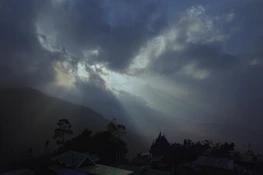 Sunlight breaking through stormy clouds over a calm landscape, evoking new opportunities.