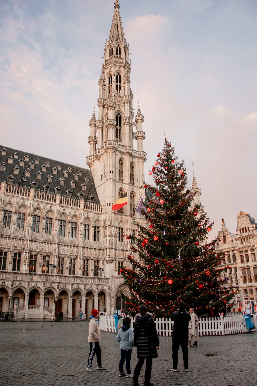 ein großes Gebäude mit einem hohen Turm und einem Baum davor mit dem Neuen Rathaus im Hintergrund