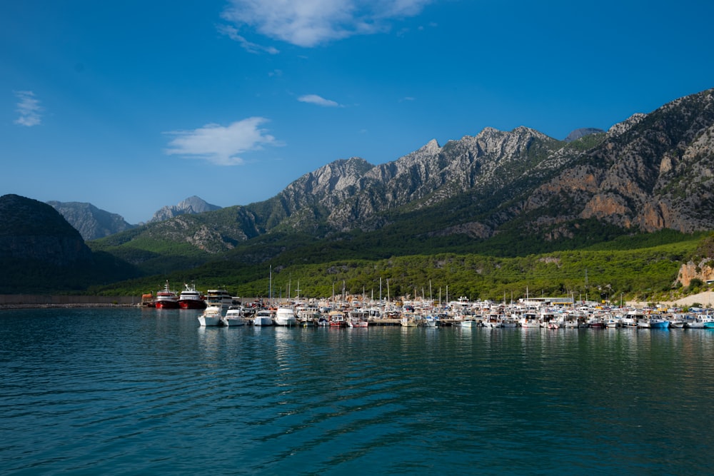 a body of water with boats in it and mountains in the background