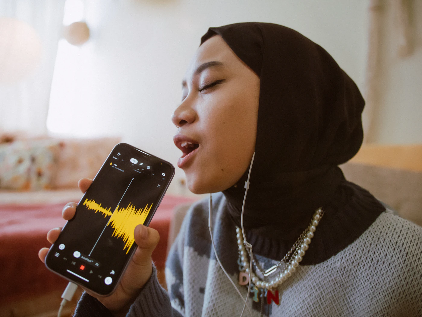 Chica joven con auriculares grabando un mensaje de voz en el móvil