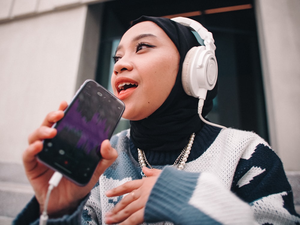 a woman wearing headphones and holding a phone