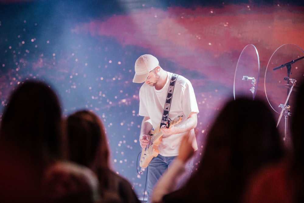 uma pessoa tocando uma guitarra em um palco com uma multidão assistindo