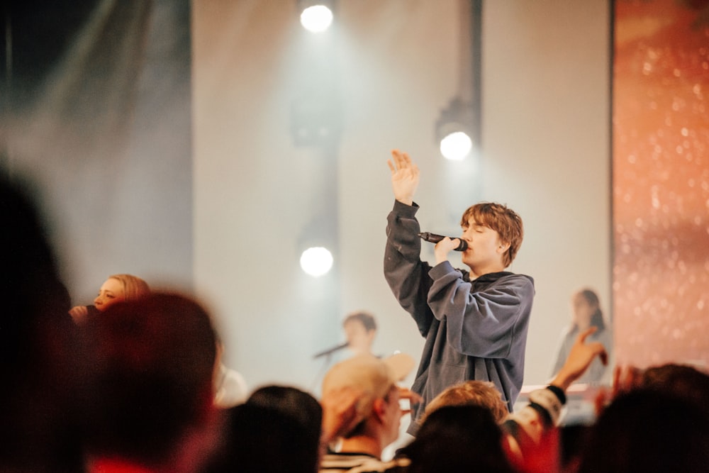 a person holding a microphone in front of a crowd