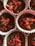 Several chocolate cupcake batter portions are placed in white and pink paper liners, topped with slices of strawberries, pink wafer pieces, and chocolate shavings.