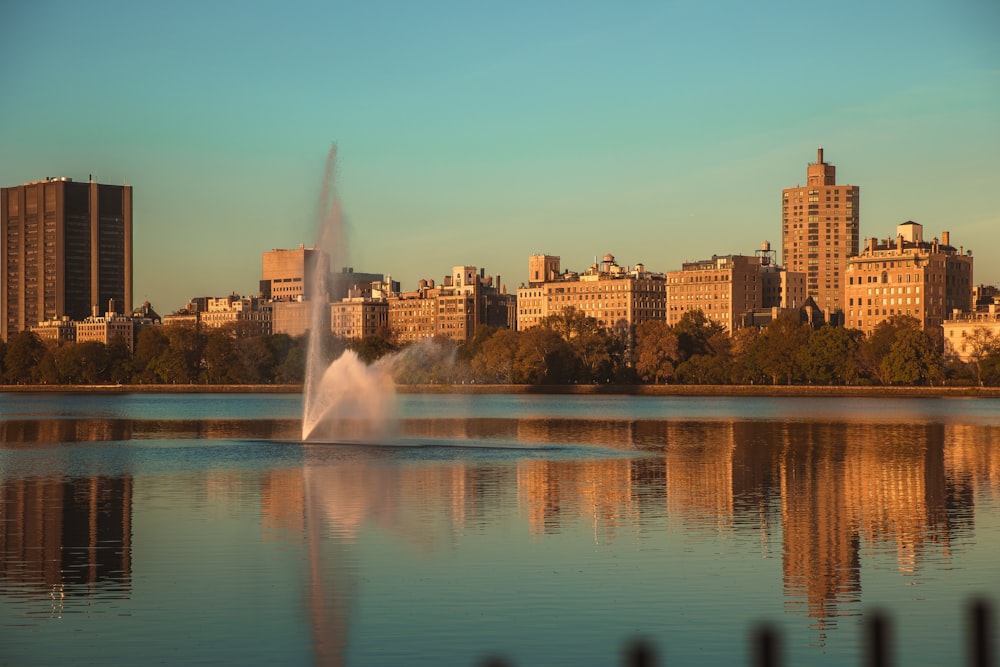a fountain in a lake with a city in the background
