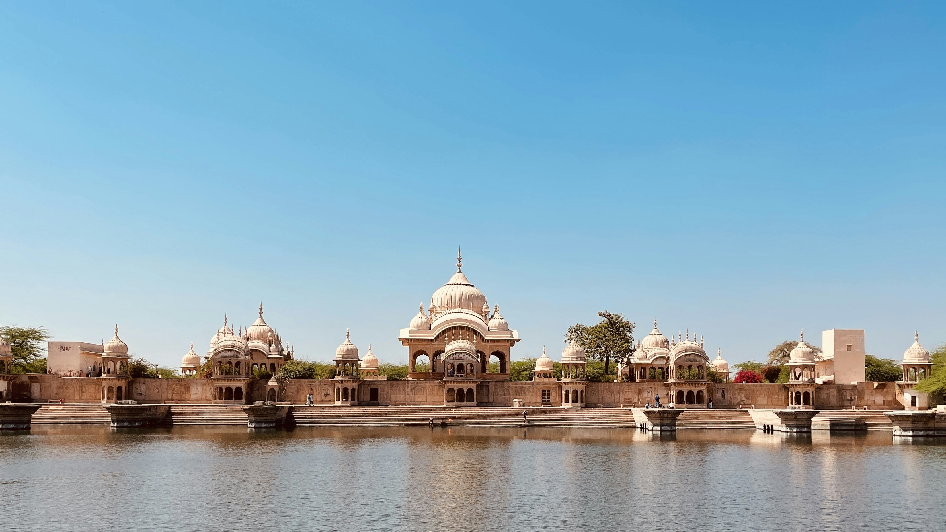 Udaipur City Palace with ornate architecture reflecting in Lake Pichola at sunset
