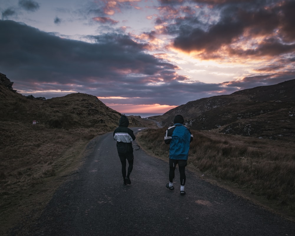 two people walking on a dirt road