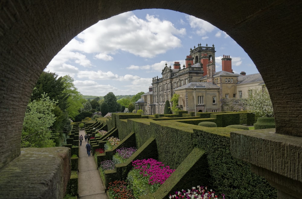 a stone walkway leading to a large building with a large garden in front