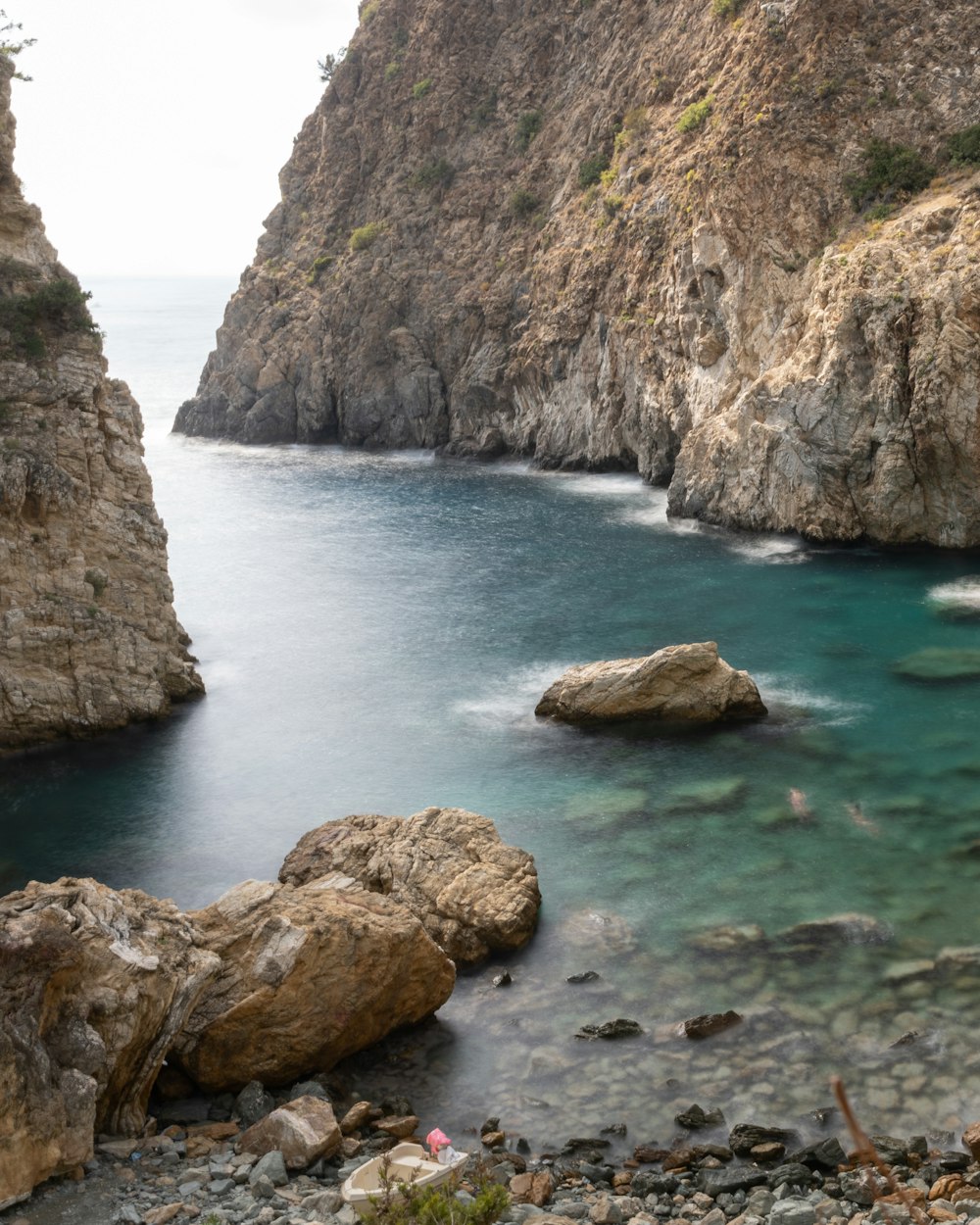 a rocky beach with a body of water and a rocky cliff