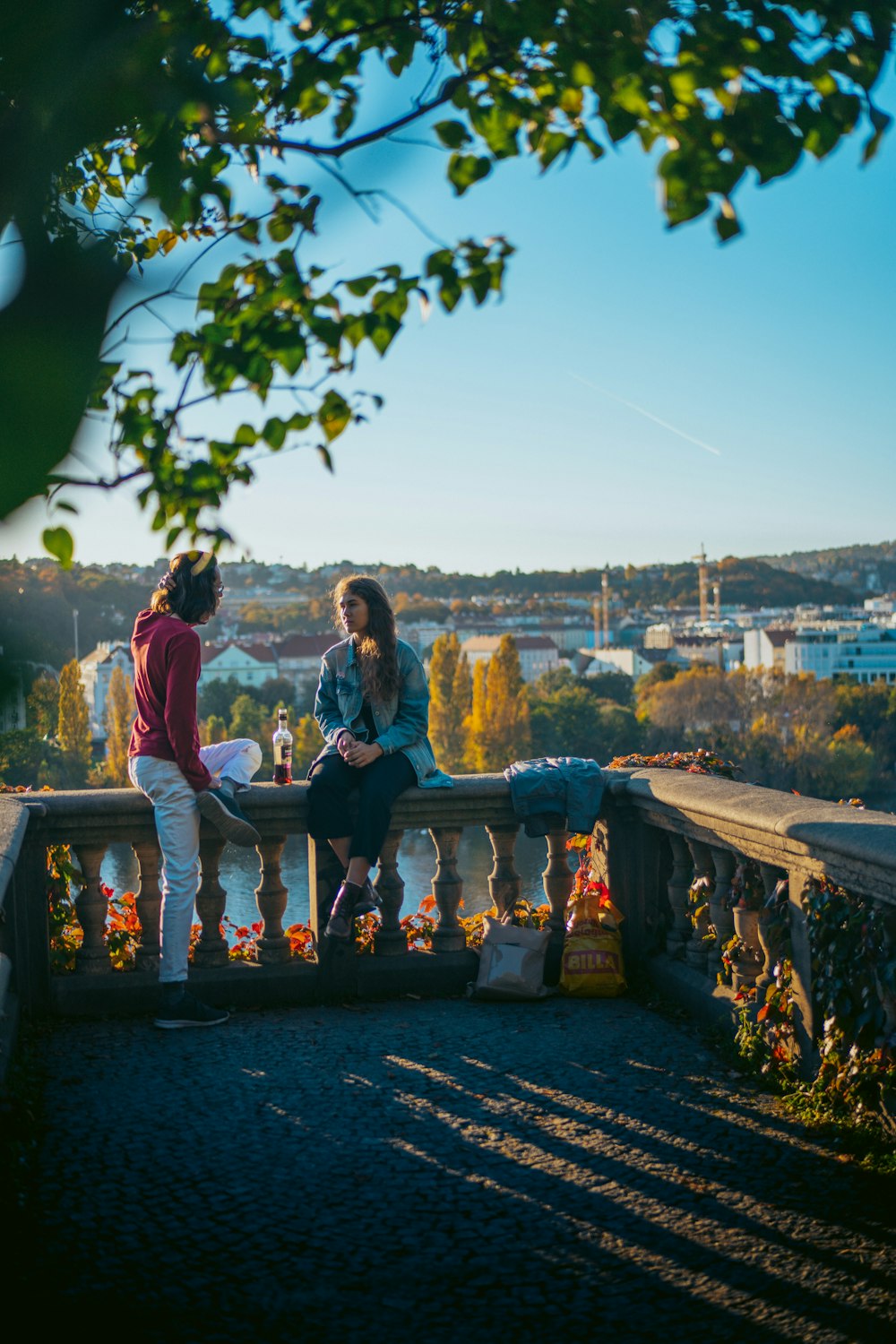 a couple of women sitting on a bench overlooking a city