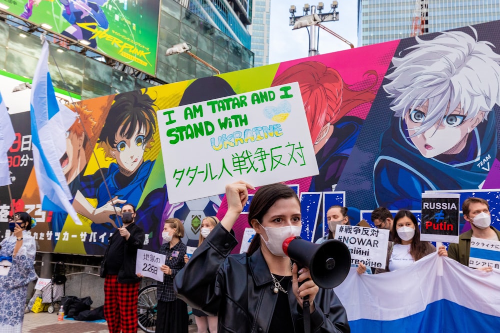 a person holding a microphone and a sign in front of a wall with cartoon characters