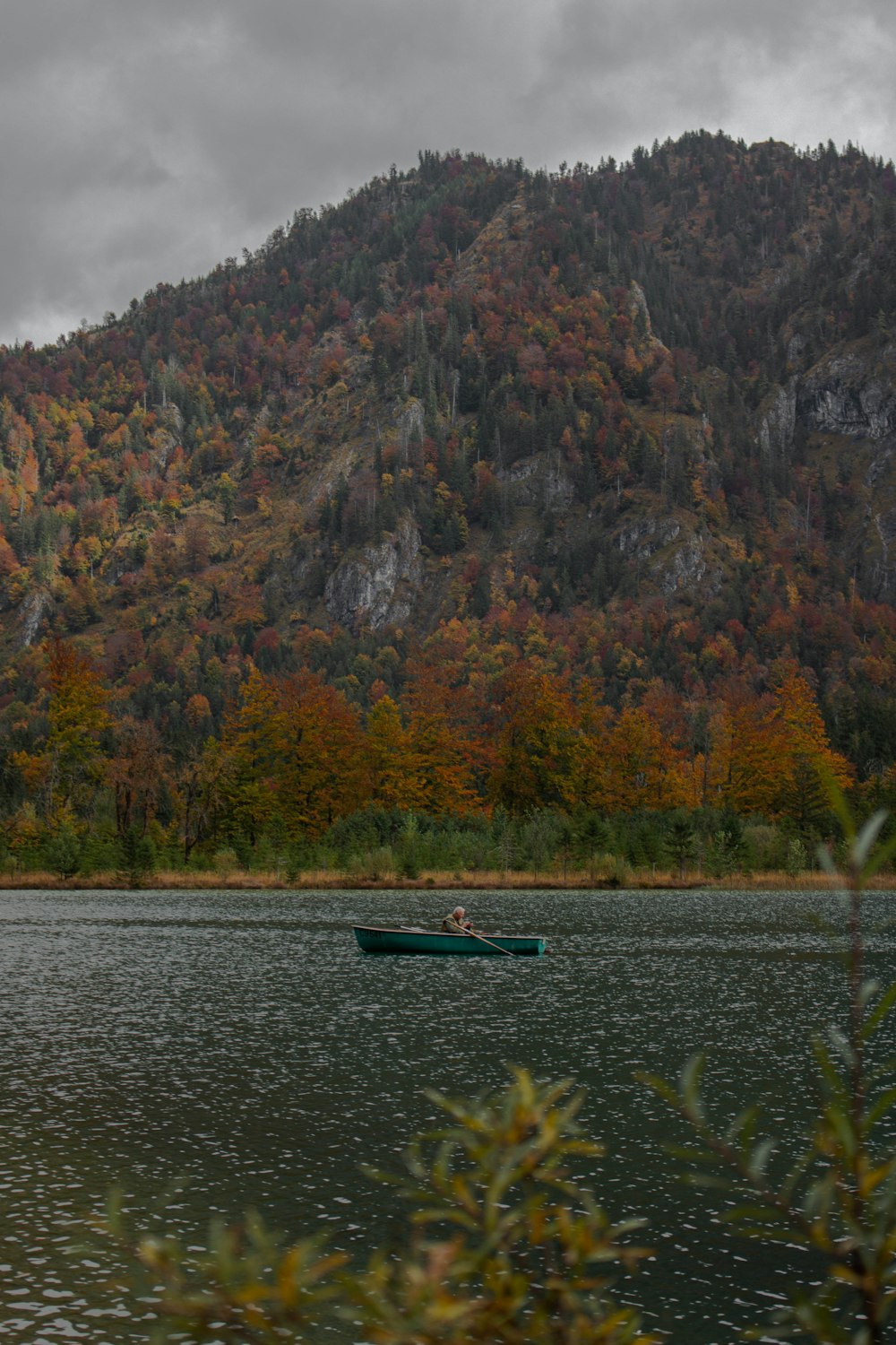 a couple people in a canoe on a lake in front of a mountain