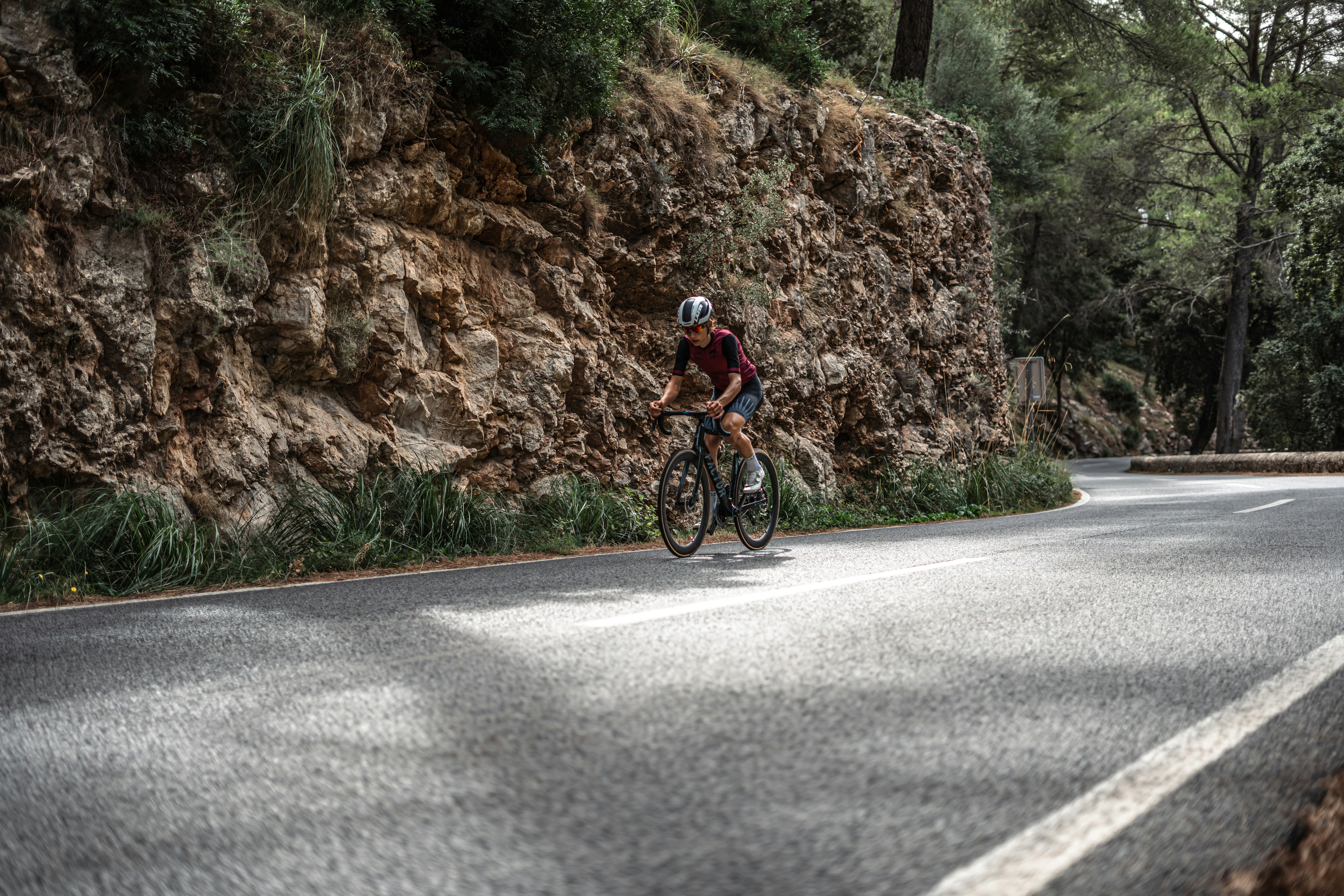 a person riding a bike on a road next to a large rock