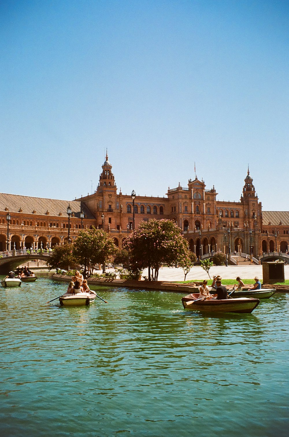 a group of people on boats in a river in front of a large building