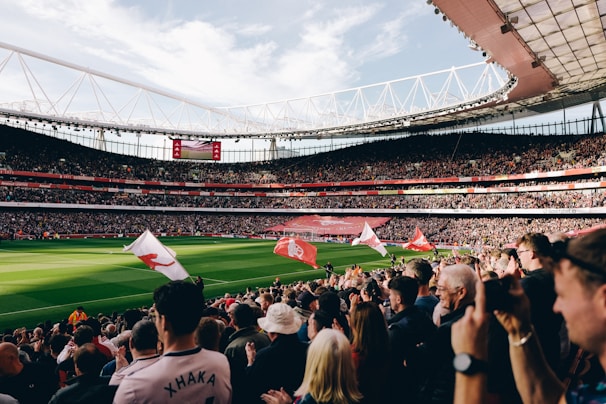 A lively scene of people cheering while watching a football match and horse races on screens.