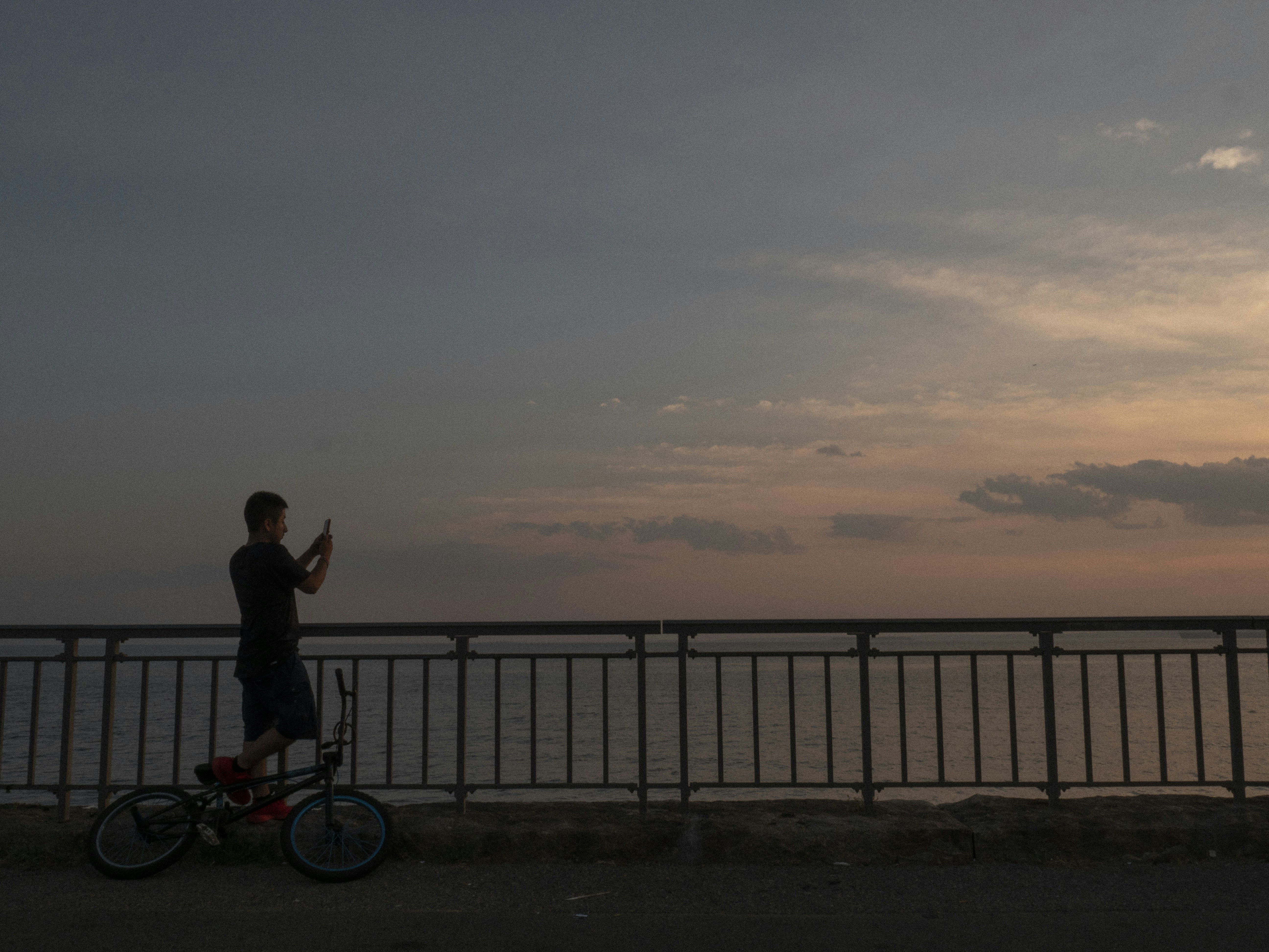 eine Person auf einem Fahrrad an einem Geländer und Wasser