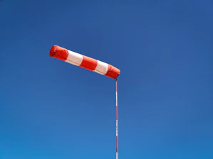 A sleek windsock gently swaying against a clear blue sky at dawn.
