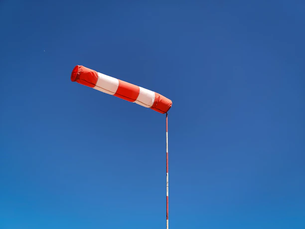 A sleek windsock gently swaying against a clear blue sky at dawn.