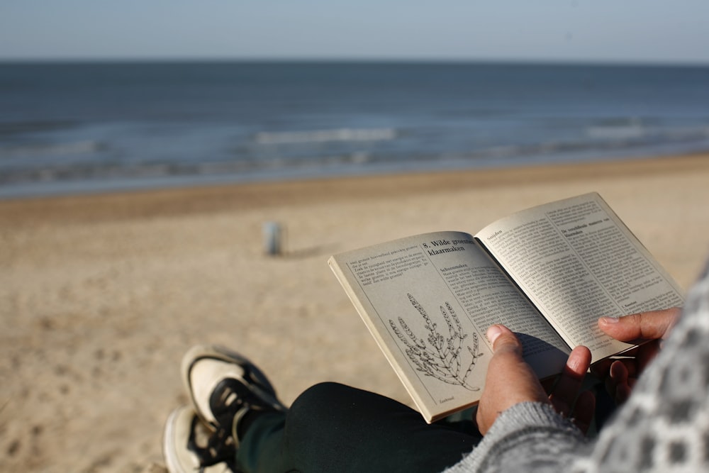 a person reading a book on a beach