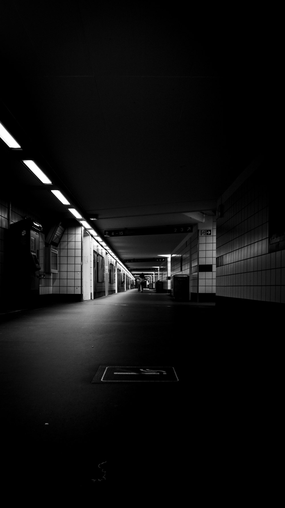 a black and white photo of a hallway with a person walking