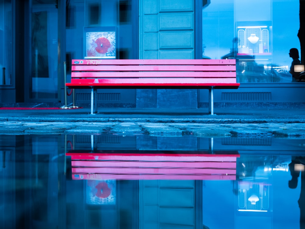 a red bench on a reflective surface