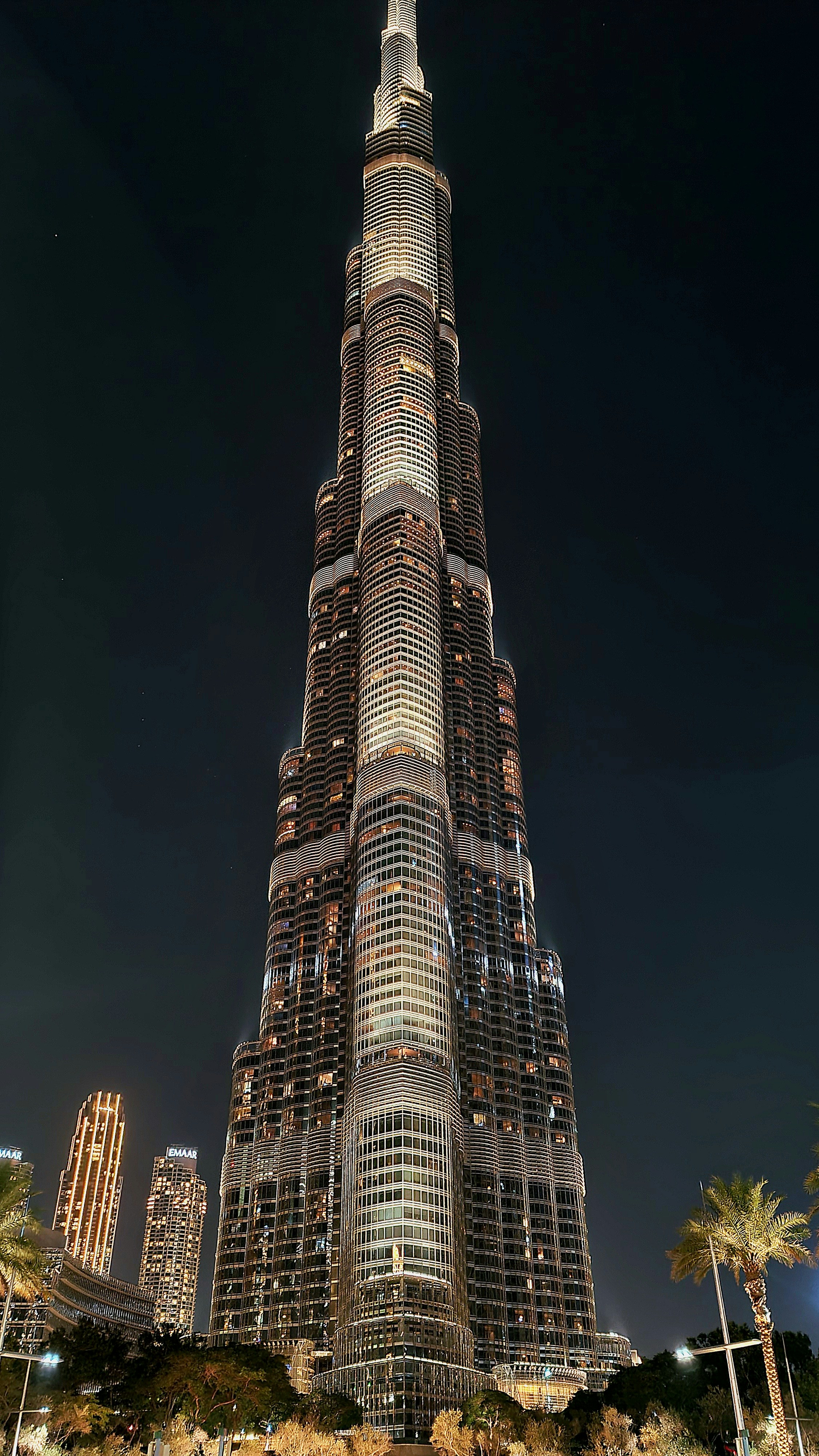Dubai skyline at night, Burj Khalifa tower lit up against dark sky, modern architecture and city lights