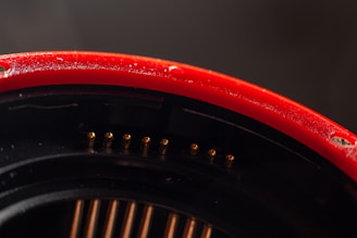 Close-up of a sleek aluminium switchboard housing with deep red accents highlighting its robust edges.