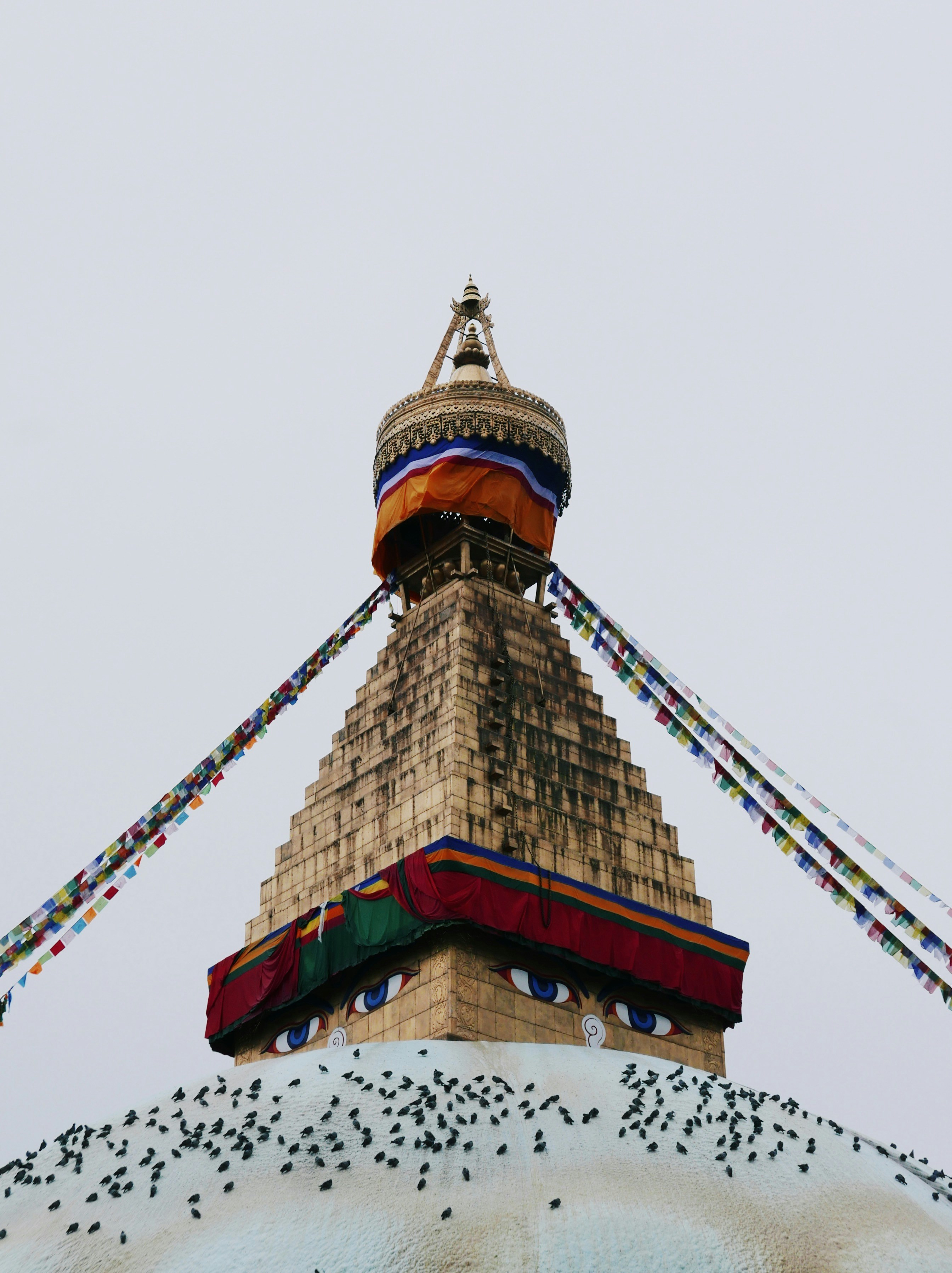a tall tower with a red and blue top with Boudhanath in the background