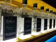 Side angle of a bottle labelling machine applying labels with perfect alignment under bright factory lights.