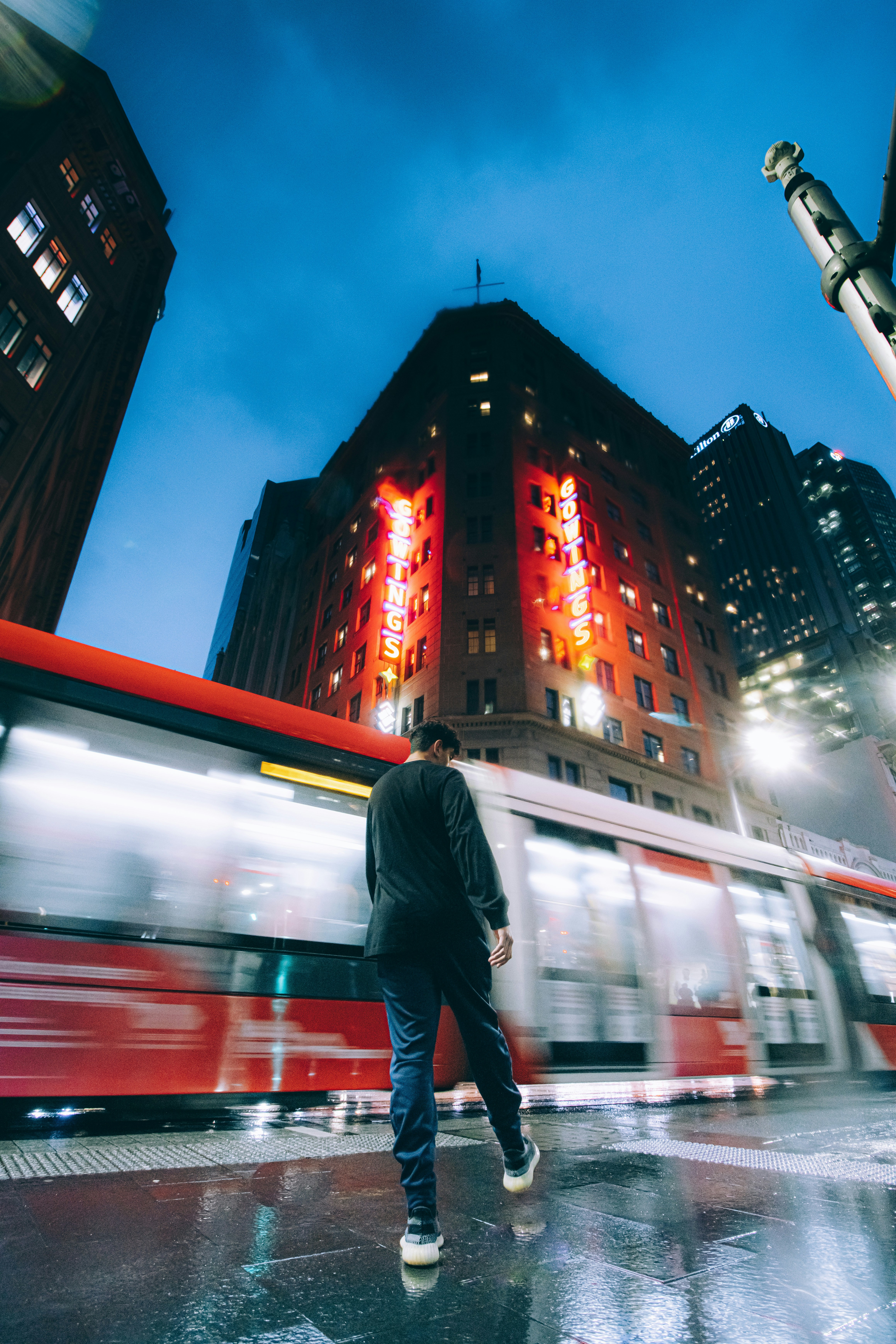 Un homme marchant sur un trottoir devant un immeuble éclairé