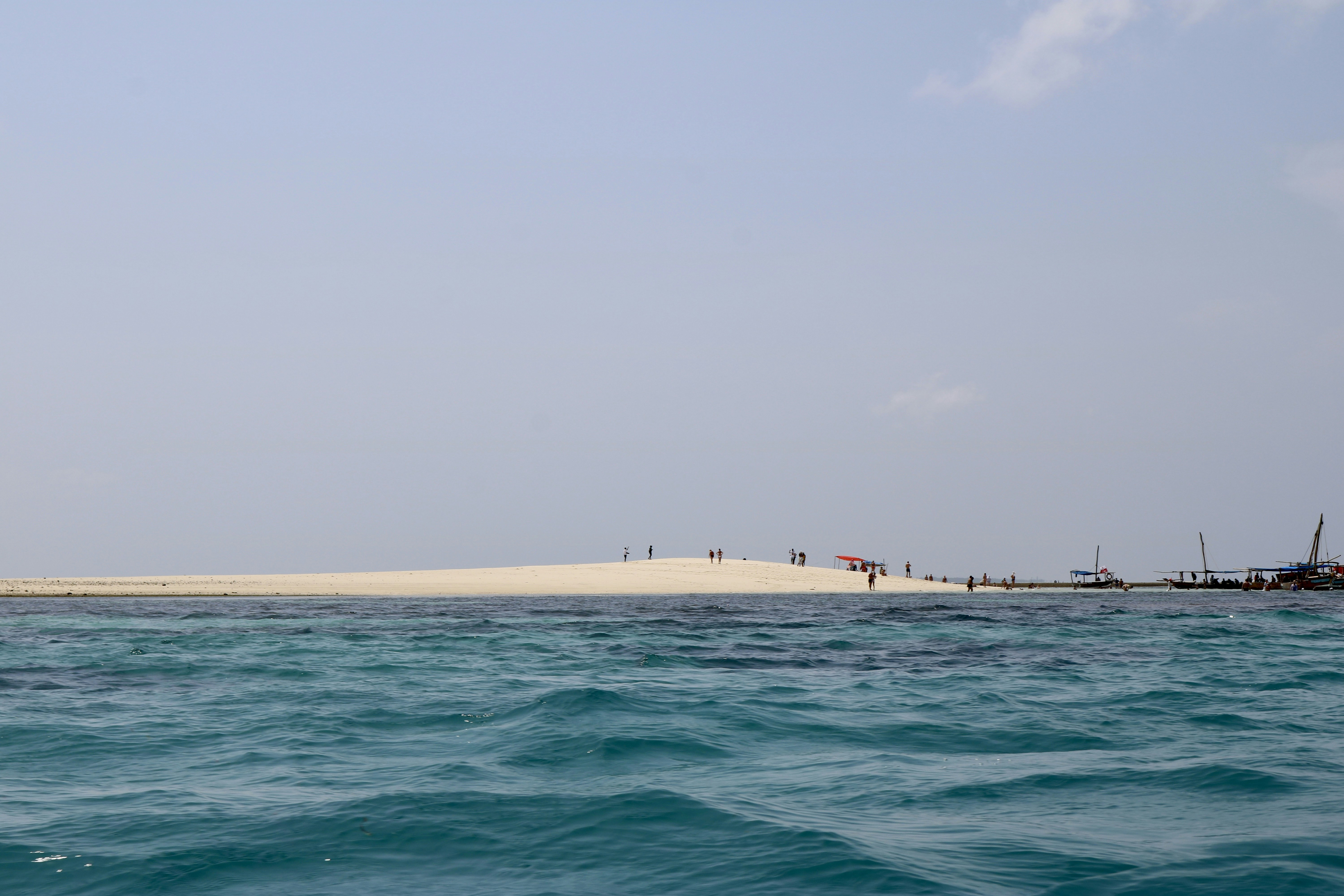a body of water with boats in it and people walking on the shore