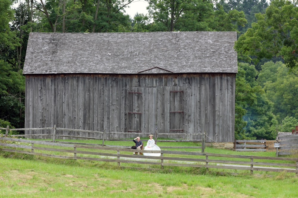 a couple sitting on a bench in front of a barn