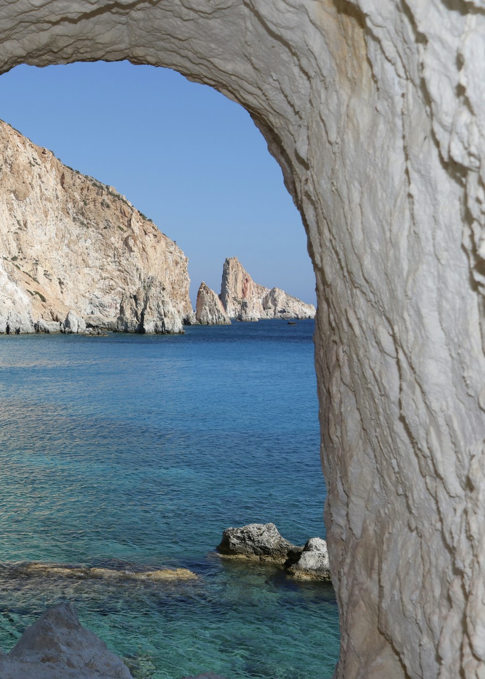 a view of the ocean through a rock archway