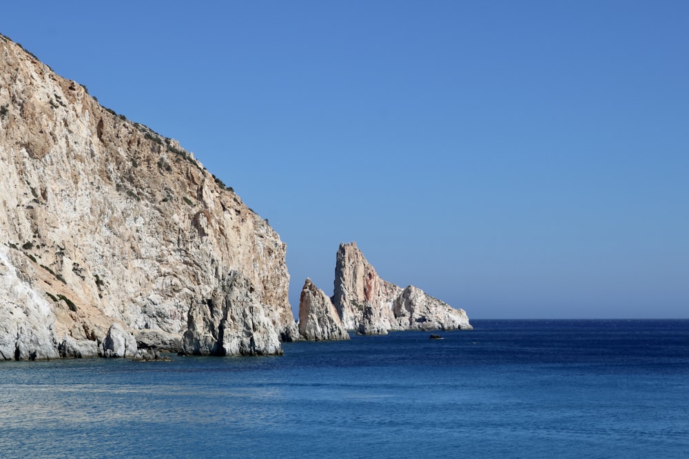 a body of water with a rocky cliff in the distance