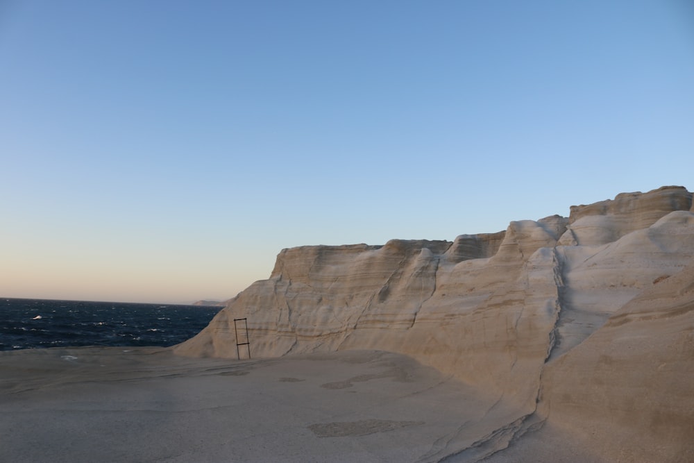 a sandy beach with a large rock cliff