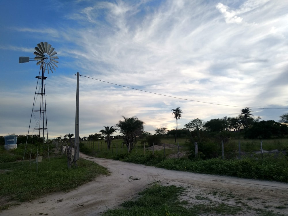a dirt road with a windmill on the side