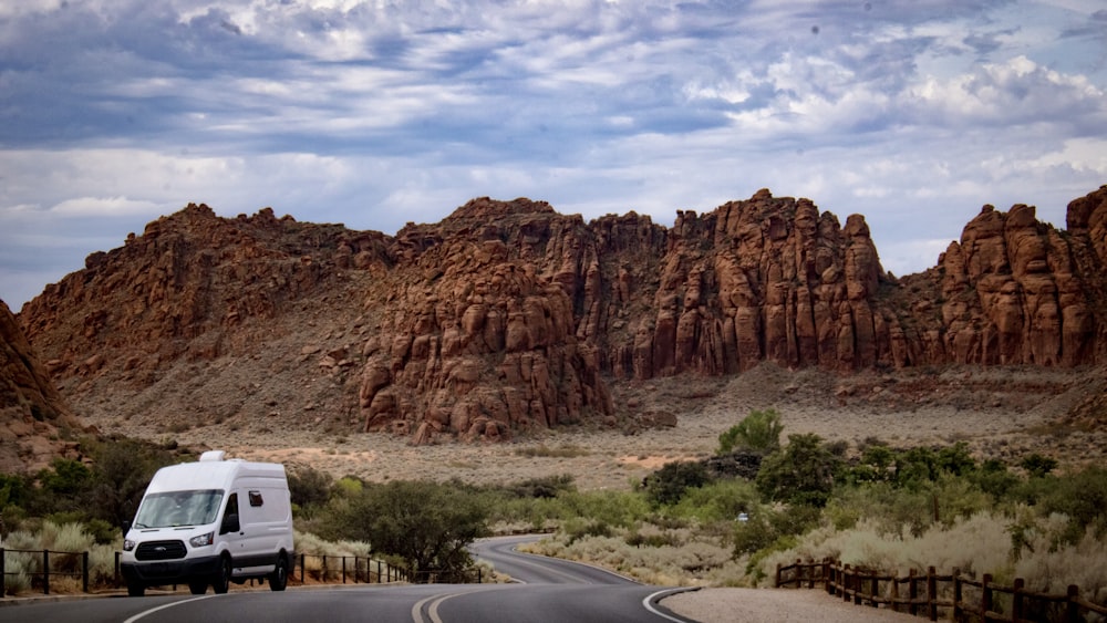 a van driving on a road in front of a rocky mountain