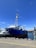 A technician inspecting maritime equipment on a dock under clear blue skies.