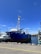 A technician inspecting maritime equipment on a dock under clear blue skies.