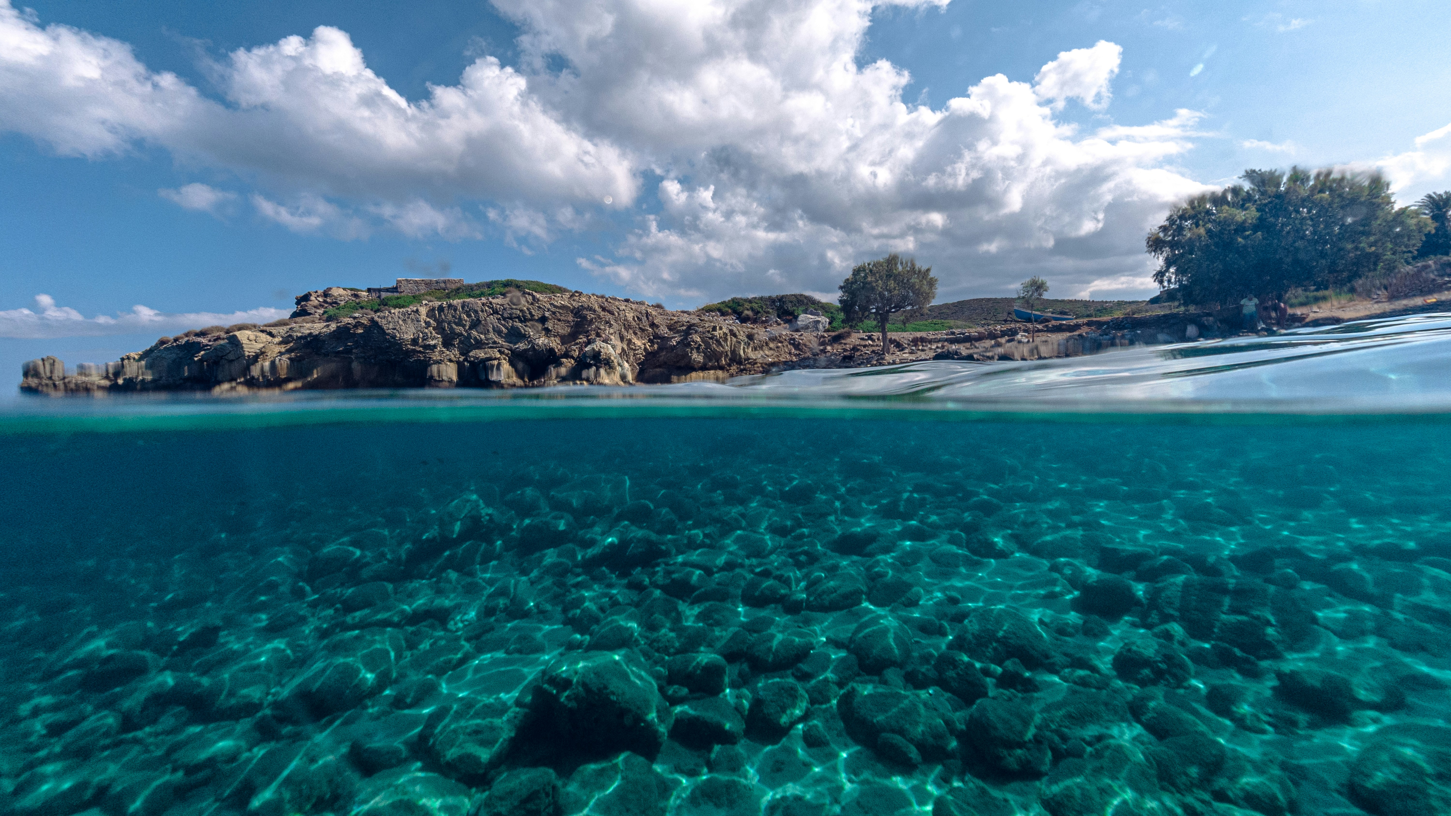 a beach with blue water and a rocky island in the distance