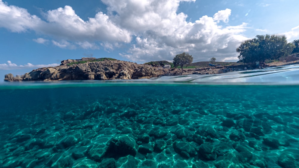 Una playa con agua azul y una isla rocosa en la distancia