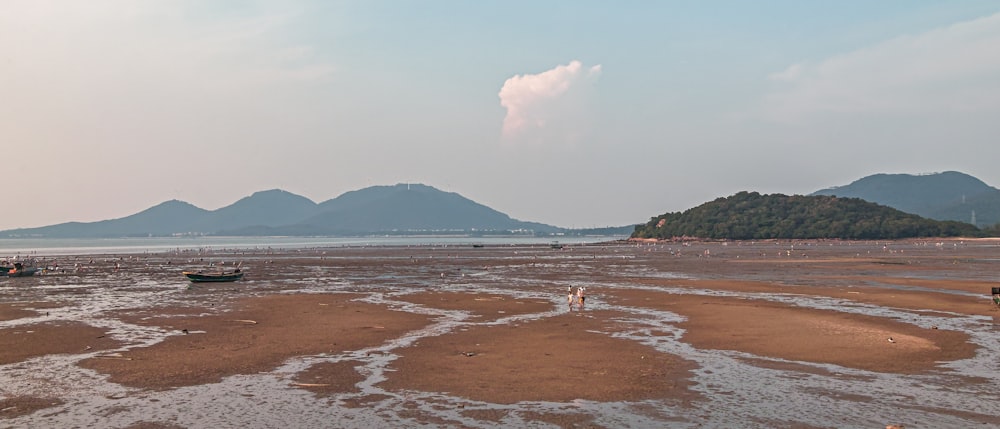 a beach with boats and mountains in the background