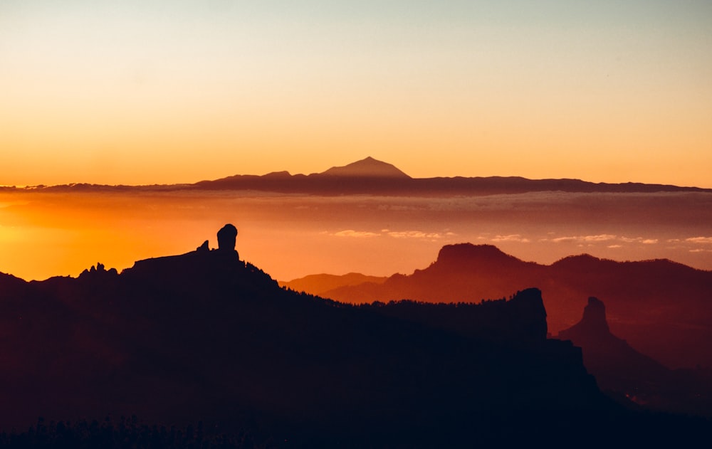 a silhouette of a mountain and a sunset