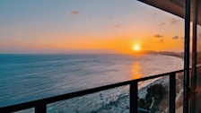 A sunset view from a hotel balcony overlooking the ocean, creating a romantic atmosphere.