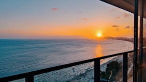 A stunning sunset view from a hotel balcony overlooking the ocean.
