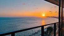 Sunset view over the calm sea from a cozy balcony.
