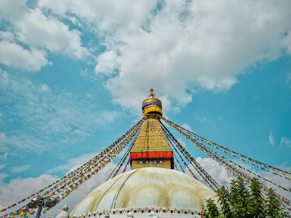 a large gold and red tower with Boudhanath in the background