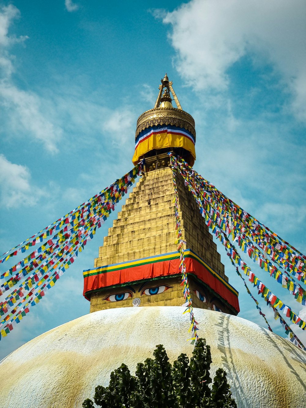 a colorful building with a gold roof with Boudhanath in the background